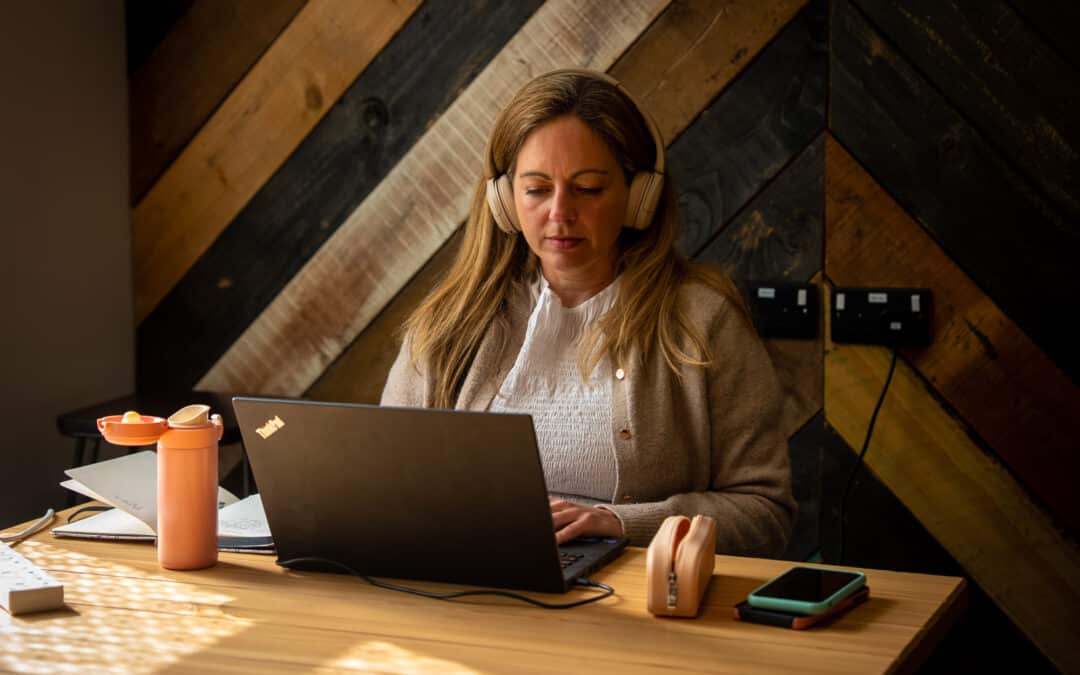 A person working at their co working desk in headphones.